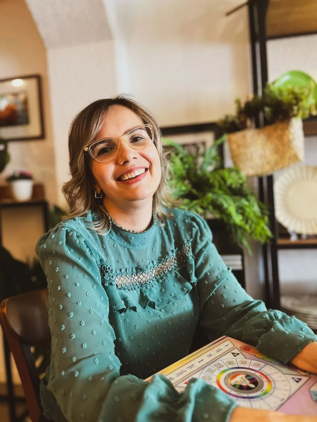 Carla Cely sorrindo enquanto utiliza o Mapa das Emoções em Hertz em sua sala de atendimento